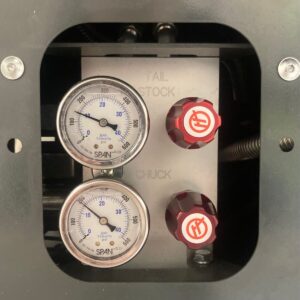 A hydraulic regulator panel for a Haas ST-15Y lathe. There are two pressure gauges on the left, and two red adjuster knobs. In this image the tailstock is set to 10 bar, and the chuck pressure is set to 12 bar.